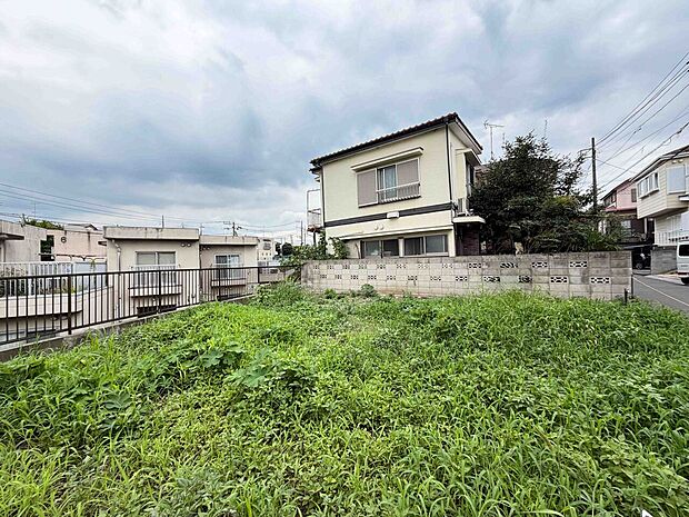 広い芝生の庭と周囲の住宅が見える敷地の様子