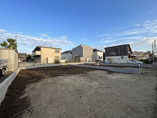 住宅地内の広い更地の敷地と周囲の建物の様子です