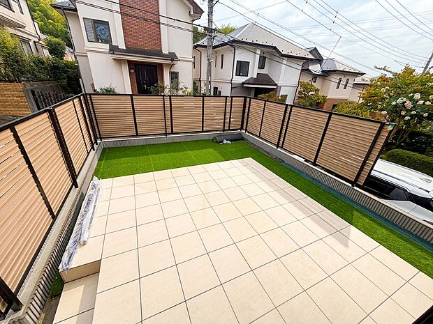 タイル敷きの広い屋上テラスと周囲の住宅環境