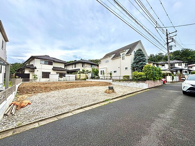 住宅街にある更地の土地、周囲に家並みが見える
