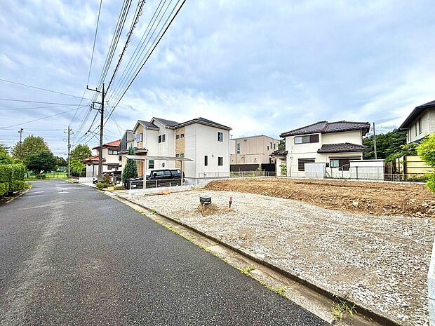 住宅街の整備された道路沿いの空地と周辺の住宅