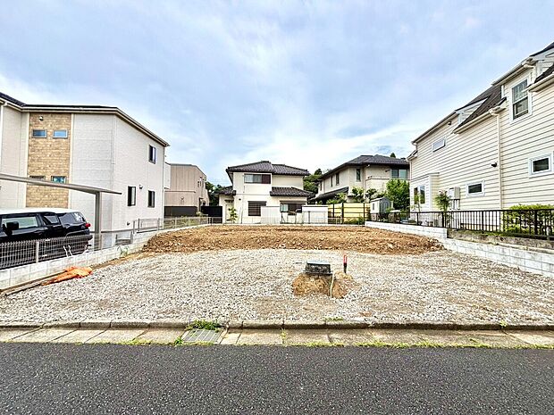 住宅地の更地で、周囲に住宅が建ち並ぶ土地の様子です