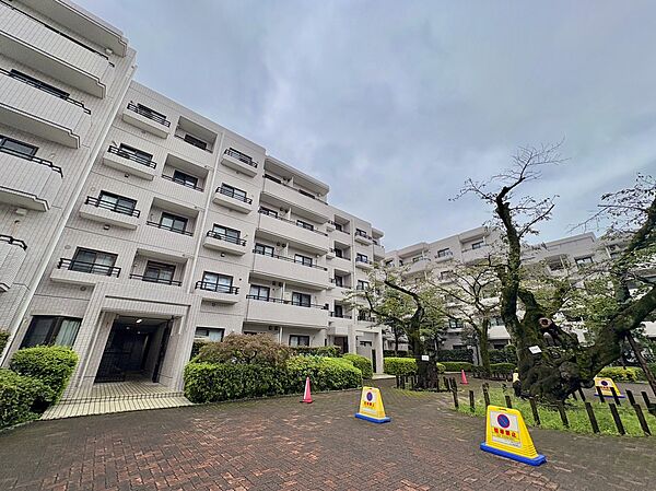 緑の植栽と遊具のある集合住宅の外観