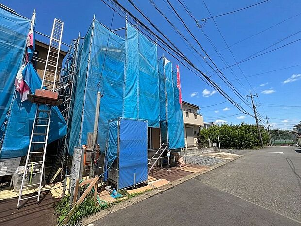 青空の下、建築中の建物と前面道路