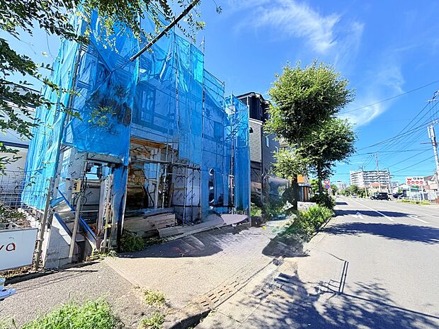 青い外壁の建物と植栽のある前面道路