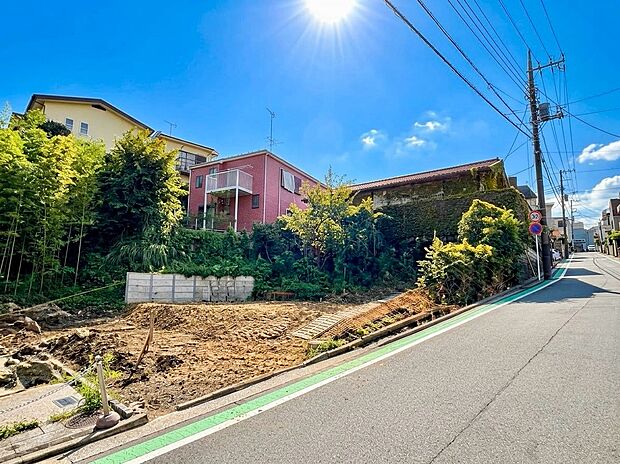 道路に面した戸建てと整地中の敷地