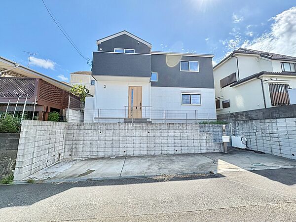 白い外壁の2階建て住宅と前面道路