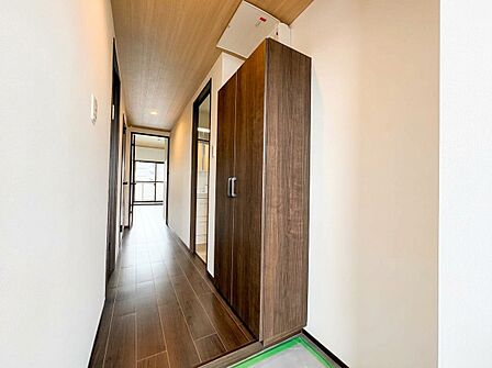 木目調の扉が並ぶ明るい室内廊下