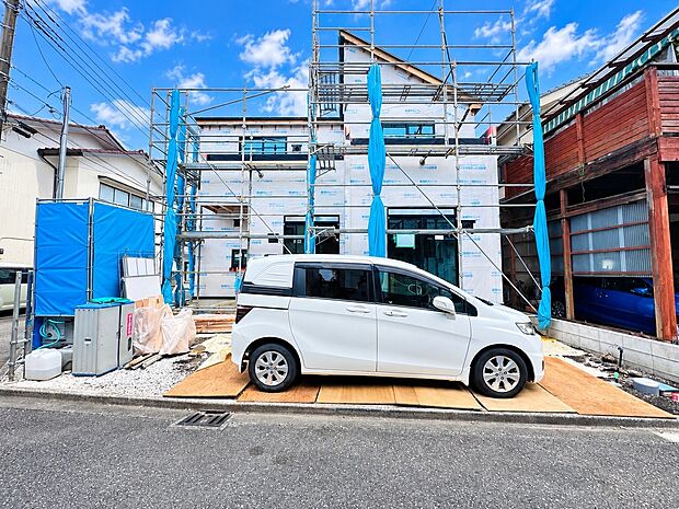 建物外観と前面道路、白い車を確認できる