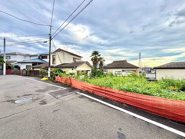 道路沿いの住宅街赤い柵と戸建てが見える
