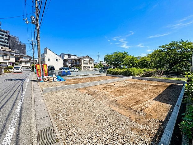 道路沿いの整形地周囲に住宅と緑が見える