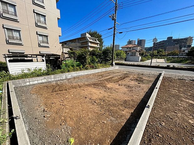 建築前の区画された更地周辺に住宅や建物が見える
