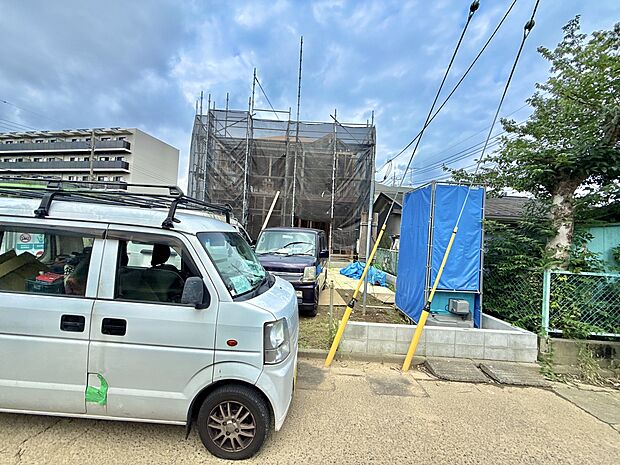 建物前に駐車スペースと車がある外観