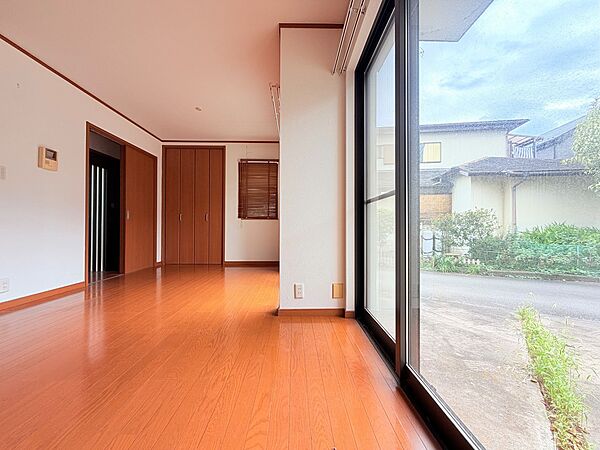窓から庭を望む明るいフローリングの洋室