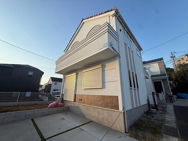 白い外壁の戸建て住宅と前面の舗装スペース