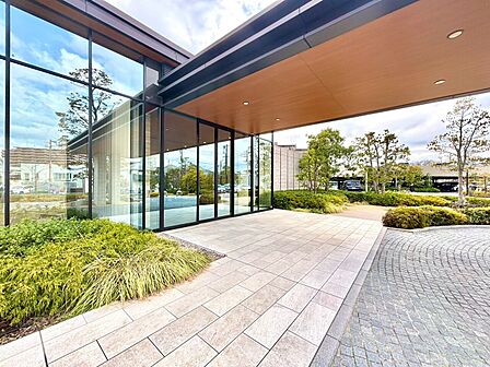 ガラス張りの建物と植栽を望むアプローチ