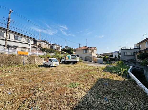 建物周辺の広い空き地と道路沿いの住宅