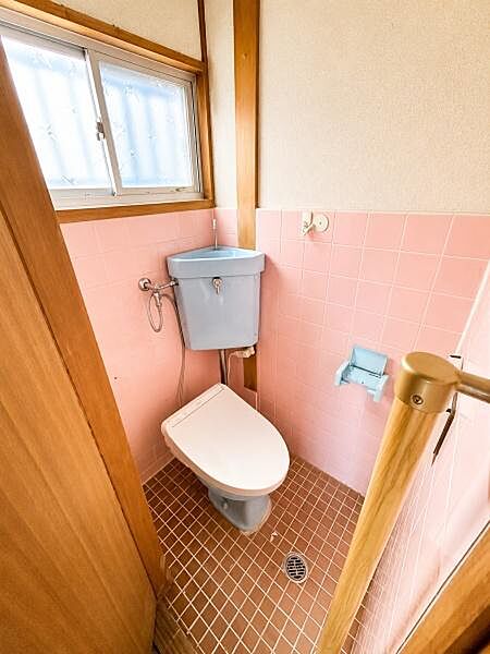 明るい色合いのタイルが印象的なトイレです。窓があり自然光がしっかりと入るため清潔感があります。扉も木目調で温かみがあります。水回りの設備も揃っており快適にご利用いただけます。