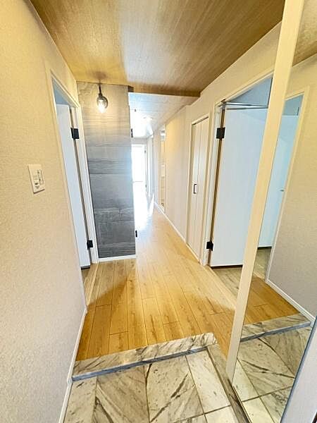 玄関には清潔感のある大理石調の床材が使われております。明るい木目のフローリングと天井が空間に統一感を与えています。廊下までの見通しが良く開放感を演出しています。