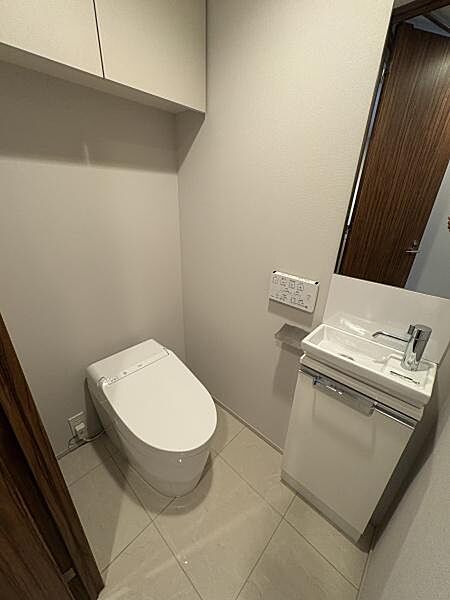 ゆとりある広さのトイレルーム。スタイリッシュなタンクレストイレで温水洗浄便座付！丸い大きな鏡がおしゃれです。