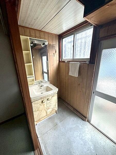 【洗面台・洗面所】窓と勝手口のガラス扉からの採光で明るい洗面室。シンプルなデザインの洗面化粧台が設置されています。※ＡＩ加工により家具や荷物の消し加工を行っております。