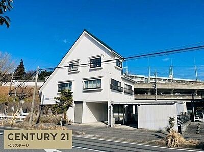 外観：青空に映える存在感のある外観が魅力の3階建て住宅。敷地内には複数台の駐車スペースを確保し、ガレージも備えています。開放感のある立地と個性的な住まいをお探しの方におすすめです。