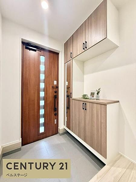木目調の玄関扉と収納がそろった、明るい玄関です！扉には縦長の窓があり、グレーの土間がすっきりした印象！吊り戸棚付きの収納で、靴もすっきり片付きます！毎日の出入りが気持ちよくなる！