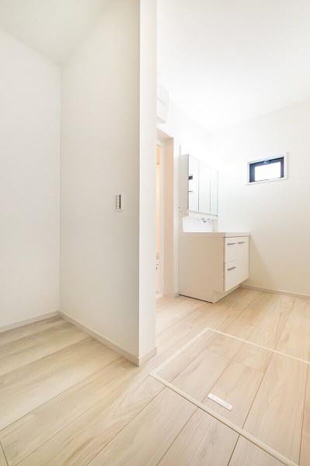 清潔感のある白を基調とした洗面室。収納豊富な三面鏡付き洗面台と、換気に便利な小窓を備えています。