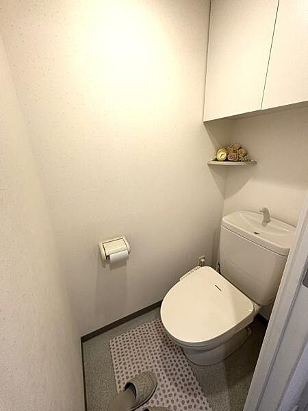 清潔感のある白を基調としたトイレです。上部には扉付きの収納棚があり、トイレットペーパー等の保管に便利。
