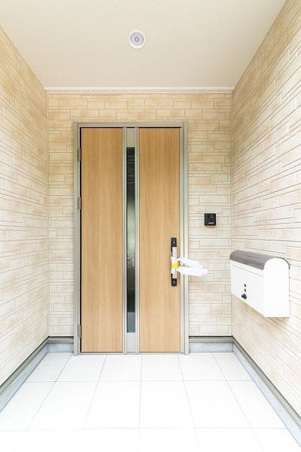 明るいタイルと木目調のドアが迎える玄関。爽やかな光が差し込む上質なエントランス。