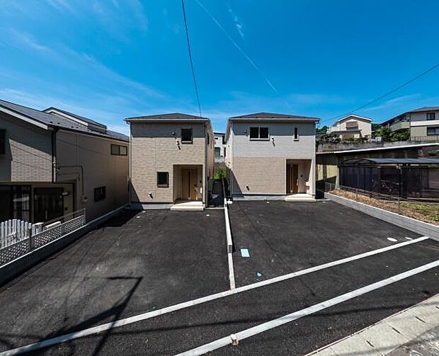 並列駐車可能なゆとりのカースペース。青空に映えるツートンカラーのモダンな新築2棟。