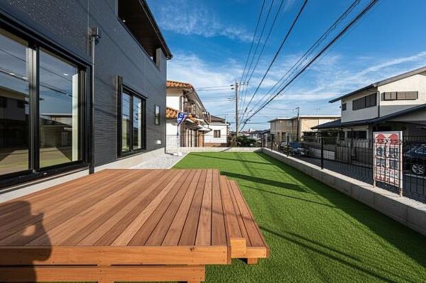 外壁と調和するモダンなウッドデッキ。人工芝の庭が広がり、家族の笑顔が広がる空間。(本画像はCGにて家具やウッドデッキ等を配置しております。実際に家具等はおかれておりません。)