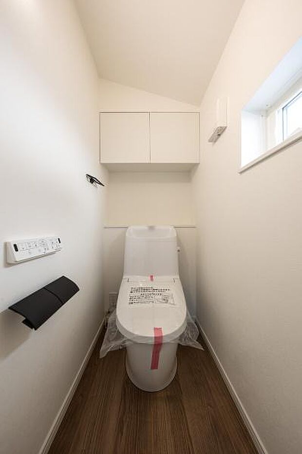 衛生的な温水洗浄便座付きトイレ。トイレットペーパーなどを隠して収納できる吊戸棚や、換気に便利な小窓付きです。