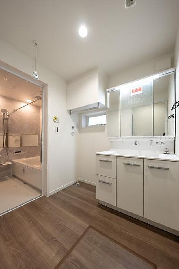 鏡裏収納付きの三面鏡洗面化粧台。小窓からの採光で明るく、タオルや洗剤をしまえる吊戸棚も備えています。