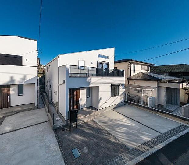 青空に映えるシャープな白い外観。開放感のあるバルコニーと、ゆとりあるカースペースを備えたモダンな邸宅です。