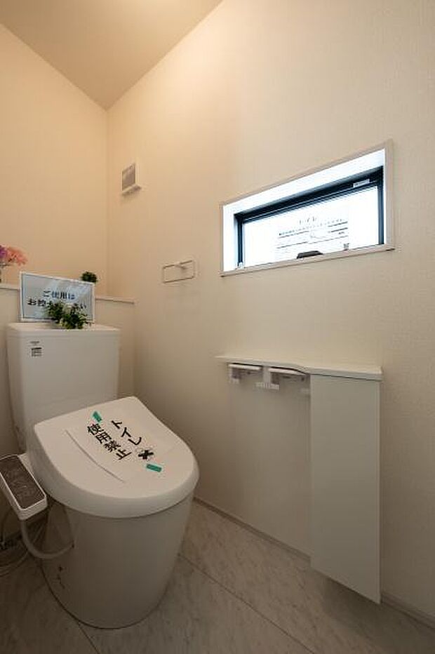 手洗いカウンターを備えた機能的なトイレ空間。小窓からの採光で明るく、毎日使う場所だからこそ清潔感と快適さを重視。