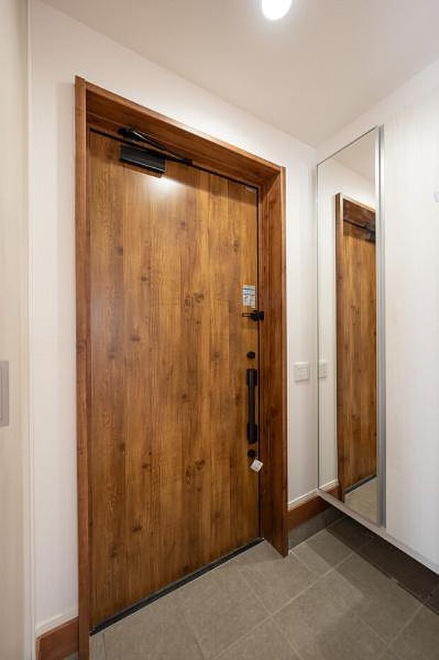 お出かけ前の身だしなみチェックに便利な大型ミラー付きの玄関。木の質感を活かした扉が、上質な住まいの顔として迎えます。