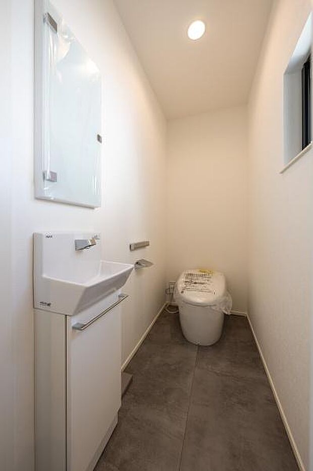 手洗いカウンター付きの清潔感あるトイレ。空間を広く見せるタンクレストイレを採用し、お手入れのしやすさにも配慮しました。