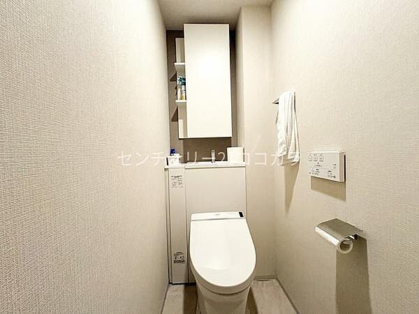 トイレシンプルで清潔感のある温水洗浄便座付きのトイレです。上部にはトイレットペーパーのストックや掃除用品を隠して収納できる便利な棚があり、トイレ内をいつもすっきりと綺麗に保つことができます！