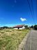 その他：青空が広がる現地写真です。周囲は開放感があり前面道路もすっきりとした印象です。敷地は両サイドにスペースがありゆとりを感じられます。家屋の周囲も自然が多く落ち着いた環境です。