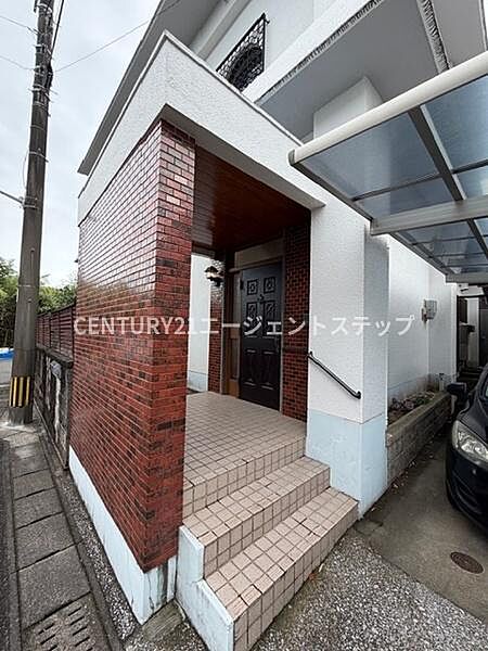 タイル貼りの階段が特徴的な玄関です。屋根付きなので雨の日も安心です。赤レンガ調の外壁が落ち着いた雰囲気を演出しています。手すりが設置されており昇降時も使いやすい設計です。