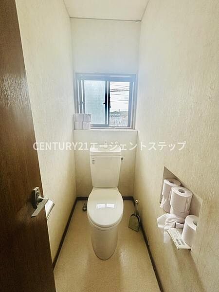 窓付きのトイレで自然光が入るため明るい印象です。壁にはトイレットペーパーの収納スペースが設けられています。清潔感のあるシンプルな内装です。使い勝手の良い配置で日々の生活にも便利です。