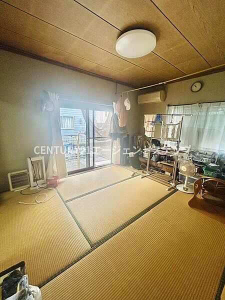 明るい日差しが差し込む和室です。縁側に面した窓が開放感を与え落ち着いた雰囲気を感じられます。畳の質感がやさしくくつろぎやすい空間です。天井照明やエアコンも設置されています。