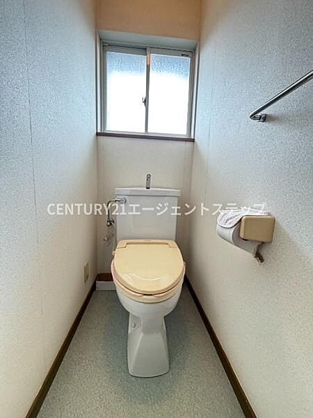 窓付きで換気がしやすいトイレです。シンプルな内装が清潔感を演出しています。ペーパーホルダーやタオル掛けも設置されています。スペースにゆとりを感じられます。