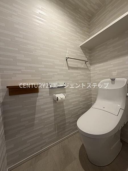 清潔感のある空間が広がるトイレです。収納棚が設置されており小物の整理もしやすいです。ペーパーホルダーやタオルバーも使いやすさを考慮した配置です。シンプルなデザインでお手入れも簡単です。