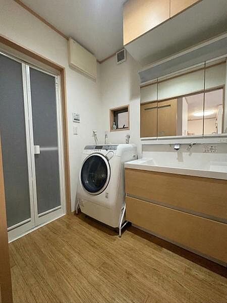 【洗面台・洗面所】洗面台、洗濯機置き場が並ぶ洗面脱衣室。※ＡＩ加工により荷物を消去した画像です。細部設備については一部描写が不足している箇所がございますので、あらかじめご了承ください。