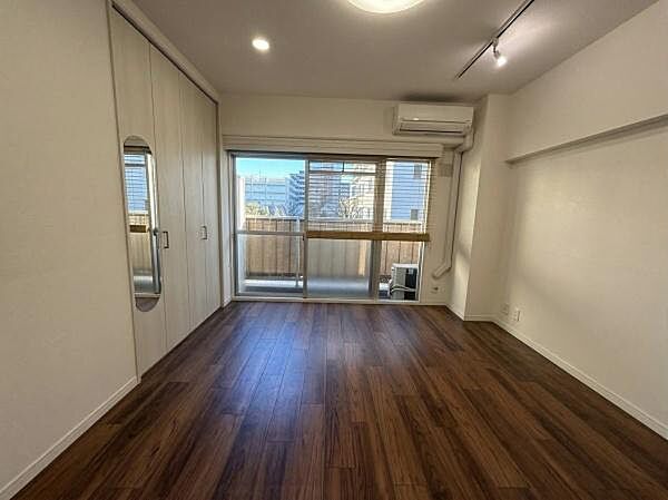 大きな窓からたっぷりと自然光が差し込むリビングです。ダークブラウンの床色が空間に落ち着きを与えています。収納スペースも確保されており使い勝手の良さが感じられます。