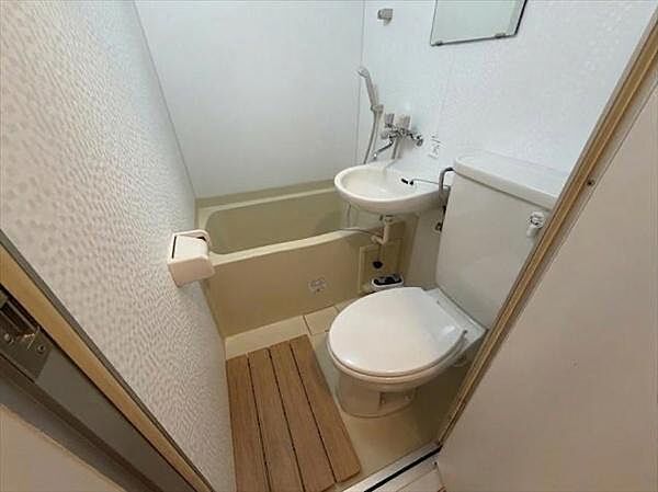 浴槽とトイレ洗面台が一体となった機能的なバス空間です。コンパクトなレイアウトで空間を有効活用しています。壁や床は明るい色合いで清潔感が感じられます。鏡や手すりも設置されています。