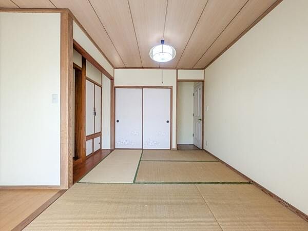 落ち着いた色合いの和室が広がります。障子やふすまのデザインも特徴的です。ゆったりとした畳スペースが魅力です。天井の照明が空間を明るく照らします。収納部分も使いやすい配置です。