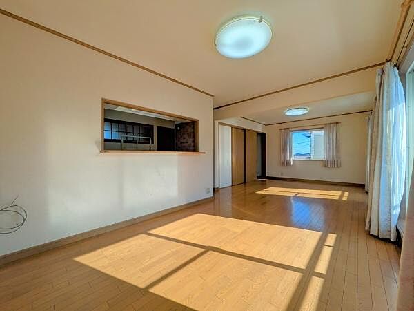 大きな窓から光が差し込む明るいリビングです。木目調のフローリングが温かみを演出しています。カウンターキッチン付きで使い勝手も良好です。広々とした空間で様々なインテリアに対応します。
